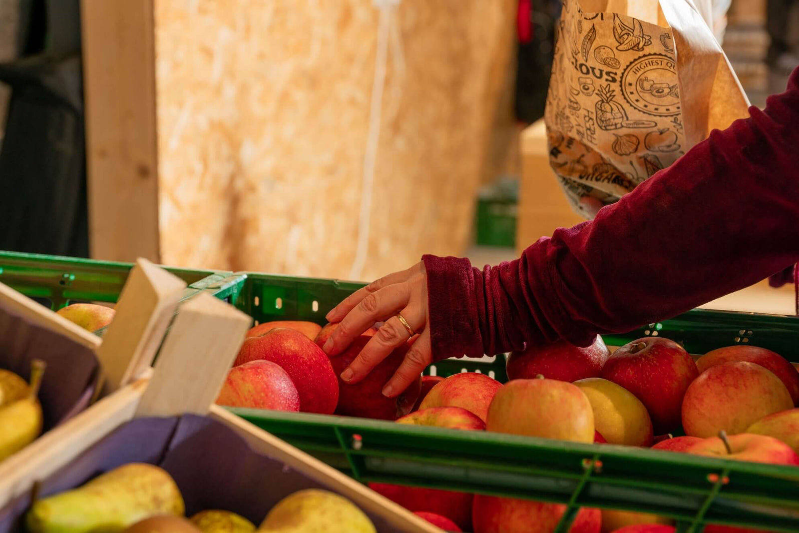 client selectionne une pomme rouge dans un casier de pommes